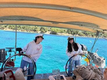 Two friends enjoy a day of sailing on a vibrant blue sea, showcasing the joy of boating adventures together.