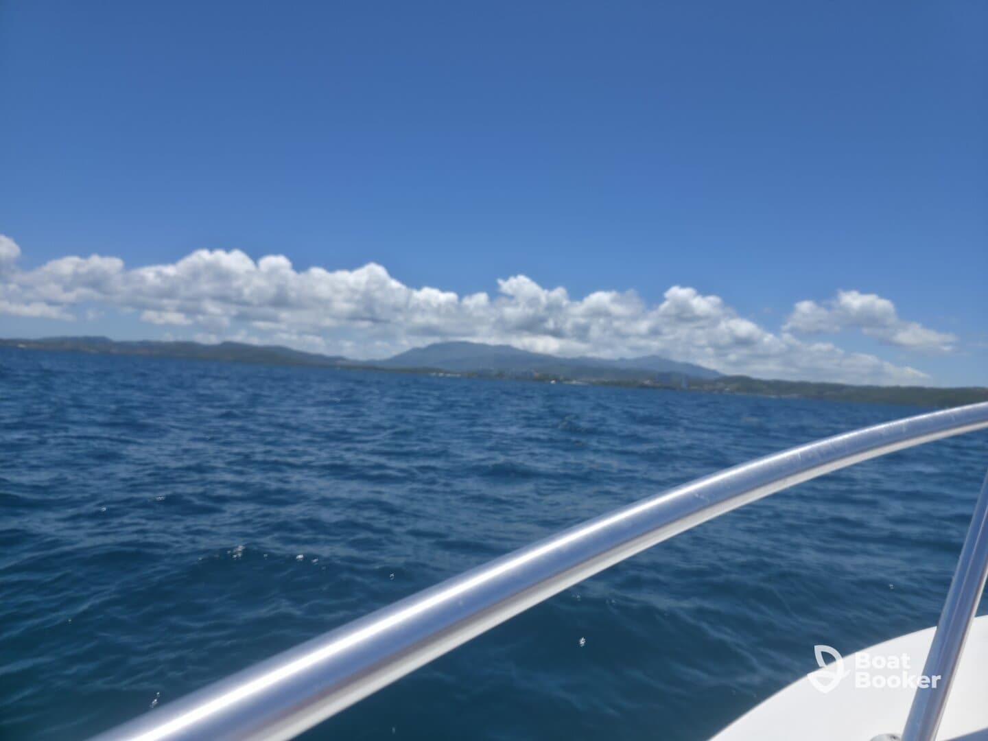 A partially obscured view of the ocean and distant land, with unclear focus on the boat's railing.