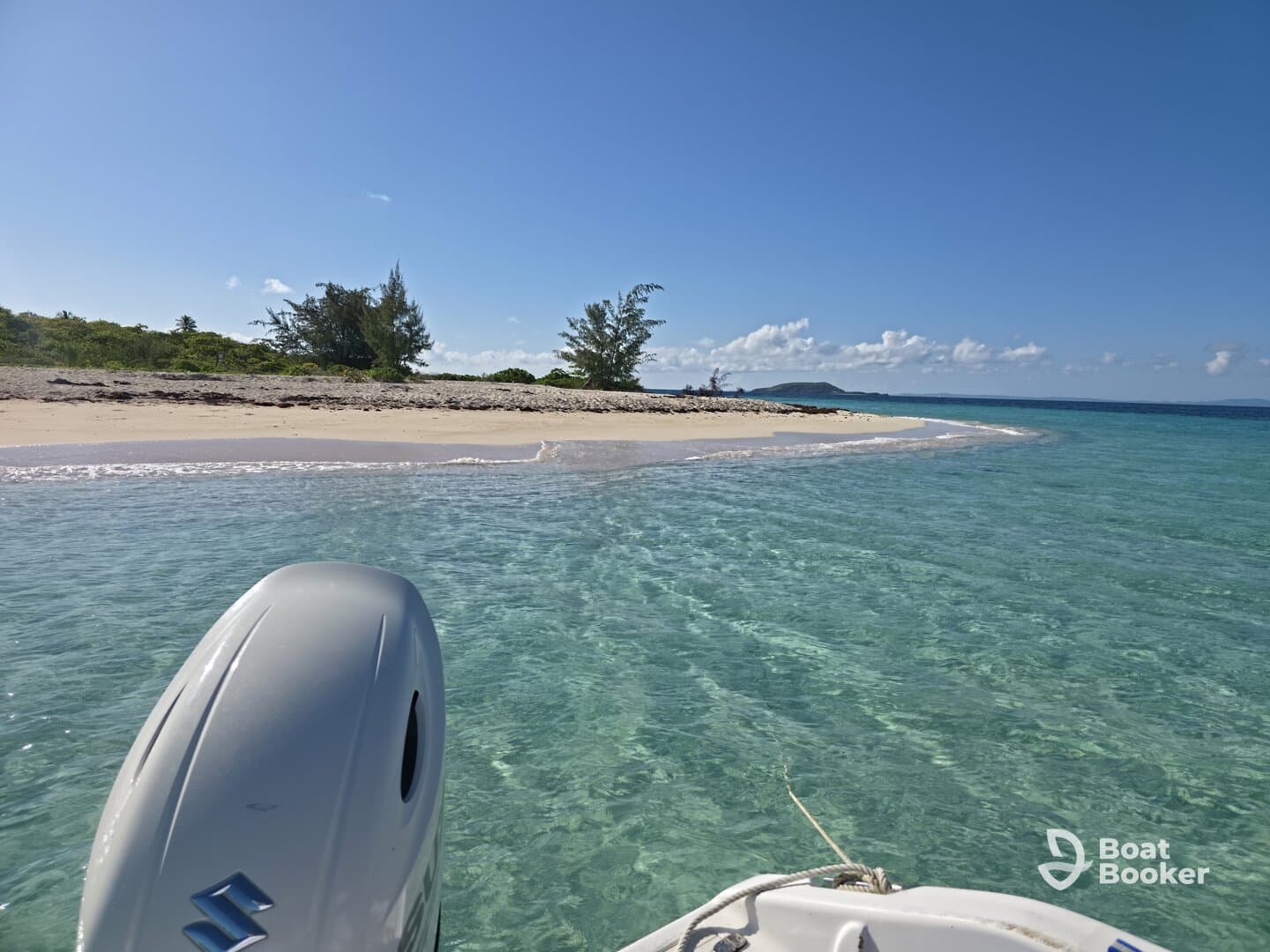 A clear view of a boat's engine with a pristine beach and turquoise waters in the background, showcasing a serene docking spot perfect for relaxation and exploration.