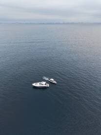 Aerial view of a yacht and a smaller boat navigating through calm waters, showcasing the beauty of boating adventures.