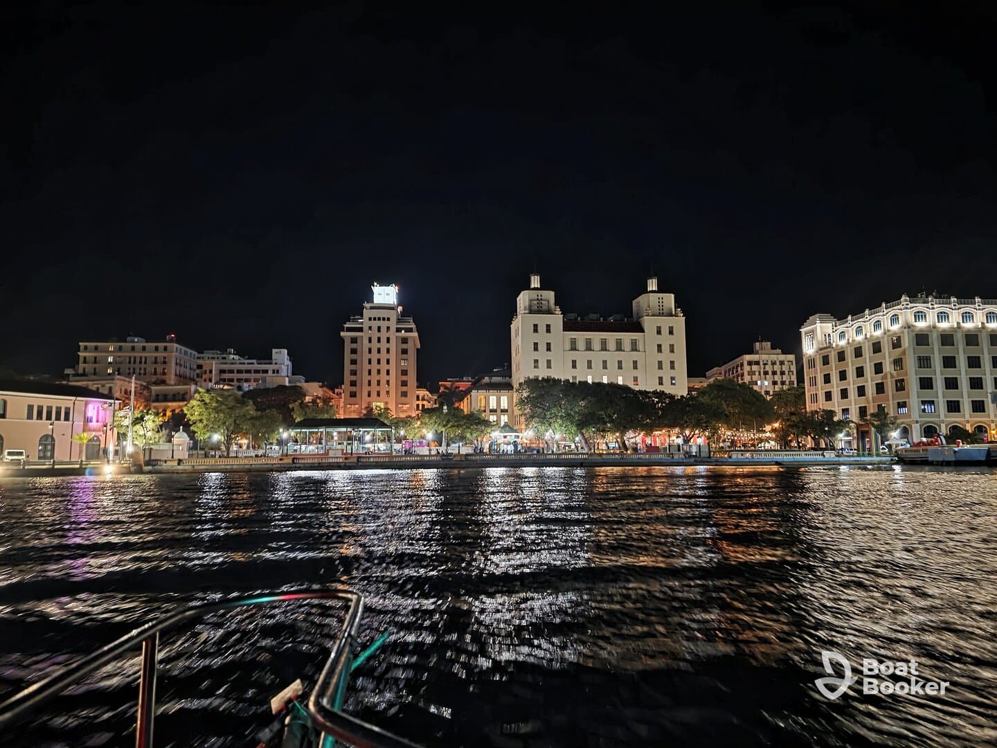 A stunning night view of a vibrant waterfront city, illuminated by colorful lights reflecting on the water — perfect for evening boat tours and sightseeing.