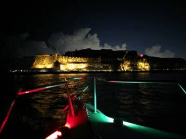 A stunning night view of a historic landmark illuminated against the dark sky, captured from a boat, showcasing the beauty of evening boat tours.