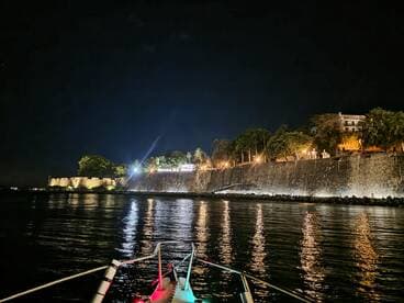 A serene night view from a boat, showcasing illuminated waterfront buildings and reflections on the water — perfect for evening cruises and sightseeing.