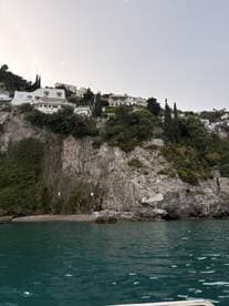 A stunning view of coastal villas perched on a rocky cliff, showcasing the beautiful landscape along the water's edge — a perfect backdrop for scenic boat tours.