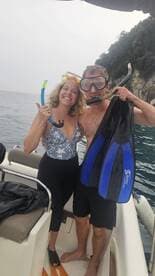 A cheerful couple prepares for snorkeling, showcasing their gear on a boat — a perfect moment for adventure seekers exploring underwater wonders.