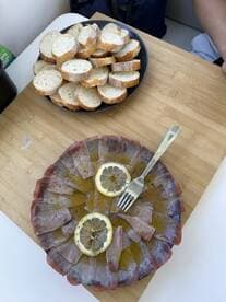 A beautifully arranged plate of sliced fish with lemon and a side of fresh bread, perfect for enjoying onboard as a delightful snack or appetizer.