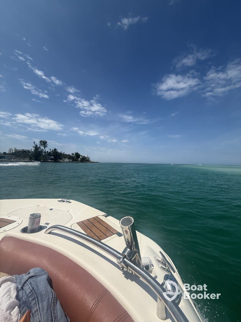 A scenic view from the bow of a boat cruising through clear waters, showcasing the beautiful coastline and blue skies — perfect for a day on the water.