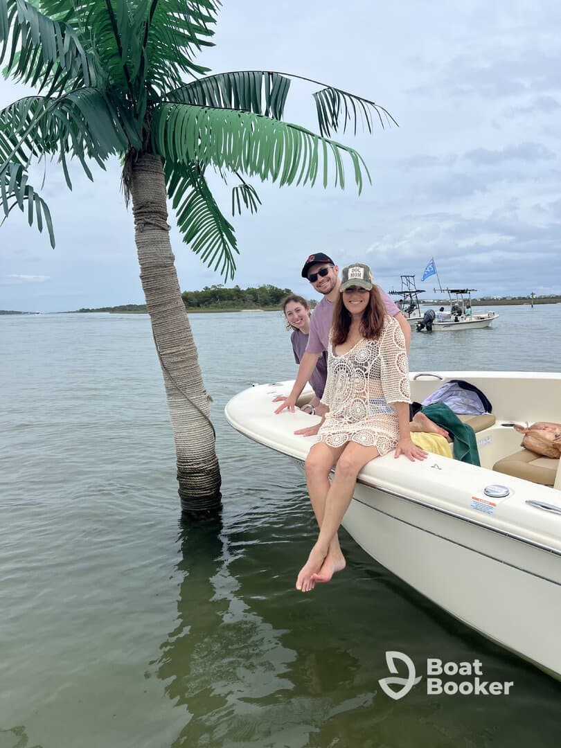 A cheerful group enjoys their time on a boat, posing playfully with a palm tree backdrop — perfect for memorable outings on the water.