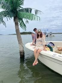 A cheerful group enjoys their time on a boat, posing playfully with a palm tree backdrop — perfect for memorable outings on the water.