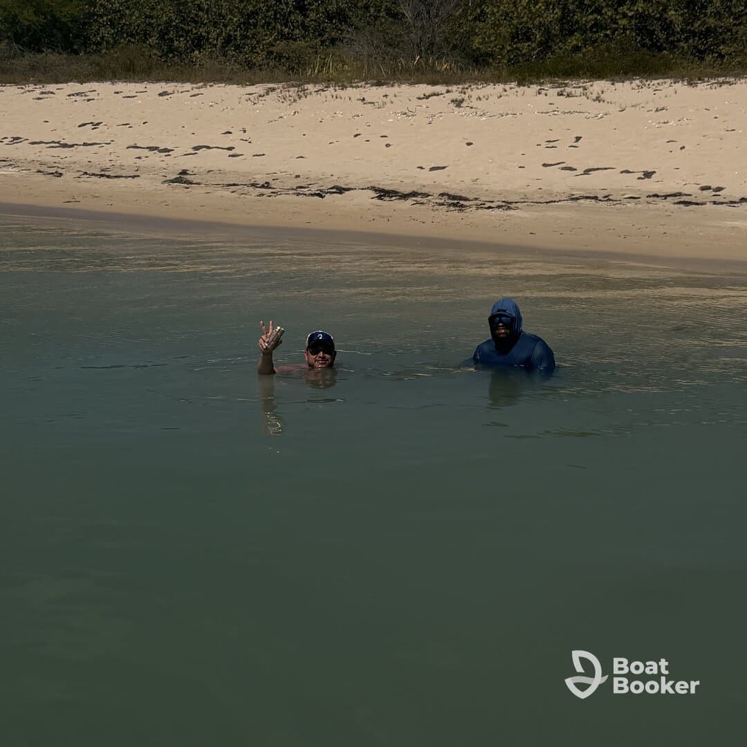 Two friends enjoy a refreshing swim in shallow waters near a sandy beach, capturing the essence of a perfect day in the sun.