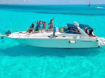A lively group celebrates aboard a boat in stunning turquoise waters, perfect for unforgettable summer adventures and fun on the water.