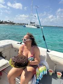 A joyful celebration on a boat as a woman holds a beautifully decorated chocolate cake, perfect for birthday parties or special occasions on the water.