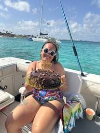 A joyful celebration on a boat as a woman holds a birthday cake, surrounded by beautiful turquoise waters — perfect for memorable birthday parties at sea.