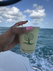 A hand holds a refreshing drink while enjoying a scenic boat ride, perfect for relaxing on the water.