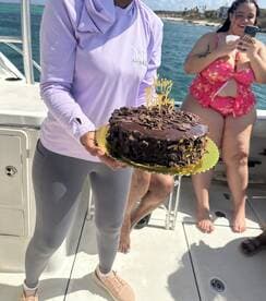 A joyful birthday celebration aboard a boat, featuring a beautifully decorated cake and happy guests enjoying the moment.