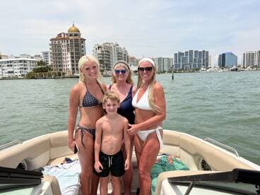 A joyful family poses on a boat with a stunning city skyline in the background, capturing a perfect day on the water.
