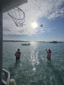 A fun day in the water with friends playing basketball under the sun, showcasing the perfect blend of relaxation and activity during a boating trip.
