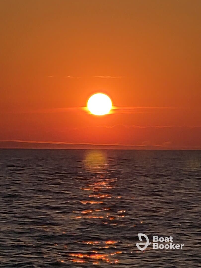 A stunning sunset over calm waters, creating a picturesque scene perfect for evening boat cruises.