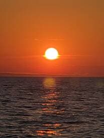 A stunning sunset over calm waters, creating a picturesque scene perfect for evening boat cruises.