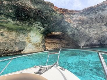A stunning view of a natural cave along the coastline, captured from the bow of a boat in crystal-clear turquoise waters — perfect for exploring scenic destinations.
