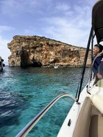 A scenic view of a rocky coastline with crystal clear waters, featuring guests enjoying a boat ride — perfect for exploring beautiful destinations.