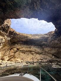 A stunning view from a boat looking up at a natural cave opening, showcasing the rugged coastline and clear waters — perfect for exploring hidden gems on the water.