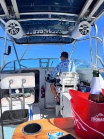 A view of the helm inside a boat, featuring a captain at the controls, showcasing the comfortable seating and essential equipment for navigating the waters.