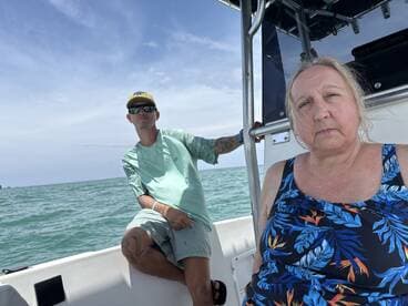 Two individuals relax on a boat, enjoying the scenic ocean view. This captures a moment of leisure on the water, perfect for a day out at sea.