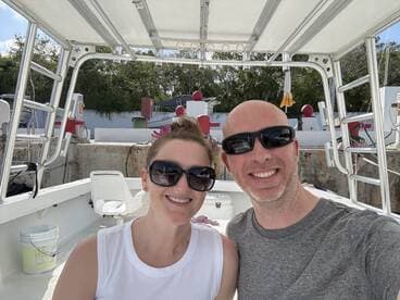 A cheerful couple poses for a selfie aboard a boat, capturing a moment of joy and adventure on the water.