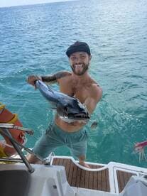 A fisherman proudly displays his catch while enjoying a day on the water, showcasing the thrill of fishing in the beautiful ocean.