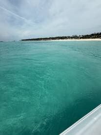A serene view of crystal-clear turquoise waters along a sandy beach, showcasing the beauty of a tranquil boating experience.