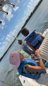 A child and an adult enjoy a day on the water, showcasing the fun of family boating adventures. The scenic backdrop adds to the excitement of their outing.