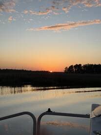 A serene sunset view from the bow of a boat, reflecting on calm waters — a perfect moment for peaceful evening cruises.