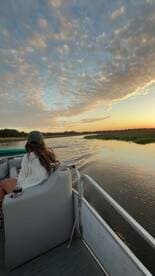 A serene sunset view from a boat, featuring a guest enjoying the peaceful waterscape — perfect for relaxation and scenic cruises.