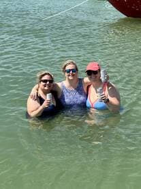 Three friends enjoy a fun day in the water, celebrating with drinks while soaking up the sun — a perfect moment for group gatherings and beach parties.