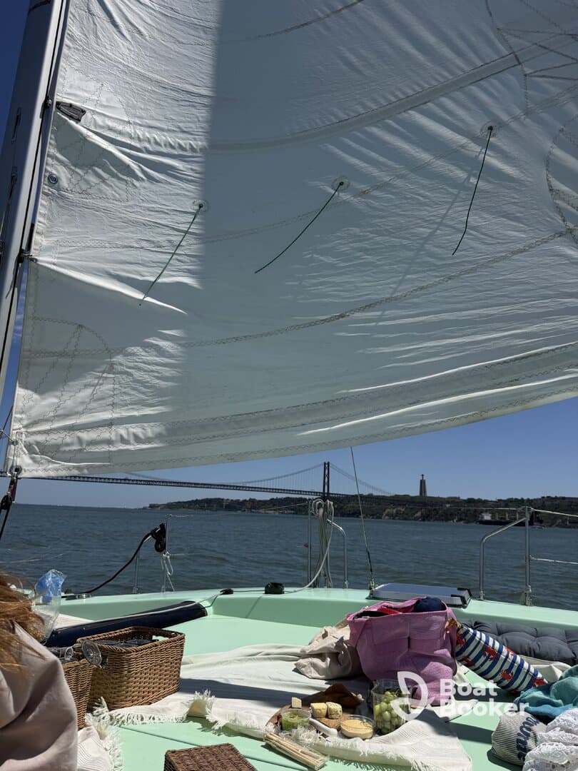A scenic view from a sailboat featuring a picnic setup on deck, with the iconic bridge in the background — perfect for a relaxing day on the water.