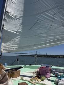 A scenic view from a sailboat featuring a picnic setup on deck, with the iconic bridge in the background — perfect for a relaxing day on the water.