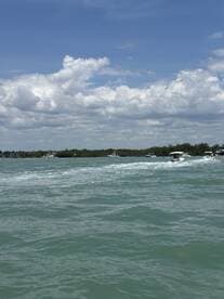 A scenic view of boats navigating through turquoise waters under a partly cloudy sky, capturing the essence of a perfect day on the water.