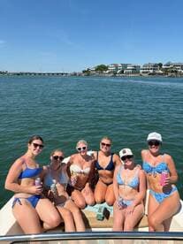 A lively group of friends enjoys a sunny day on the boat, celebrating with drinks and laughter — perfect for summer outings and beach parties.