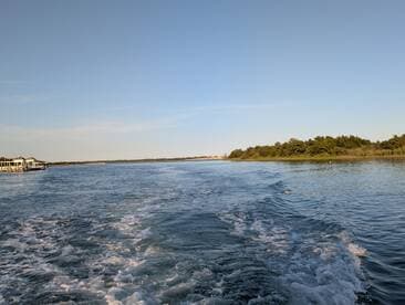A serene view of a waterway with gentle waves and a distant dock, perfect for showcasing the beauty of coastal adventures.