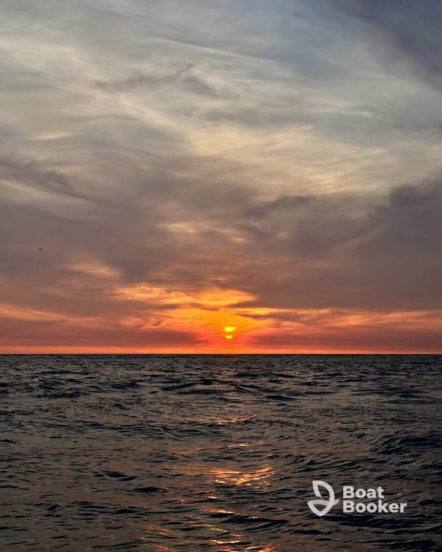 A breathtaking sunset over the ocean, casting vibrant colors across the sky and reflecting on the water — a perfect moment for relaxation and reflection on a boating adventure.
