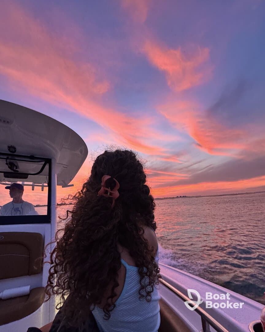 A serene sunset view from a boat, featuring a young woman enjoying the colorful sky as the boat glides through the water — perfect for capturing tranquil moments on the water.
