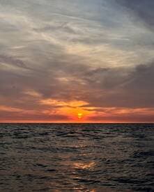A breathtaking sunset over the ocean, casting vibrant colors across the sky and reflecting on the water — a perfect moment for relaxation and reflection on a boating adventure.