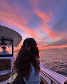 A serene sunset view from a boat, featuring a young woman enjoying the colorful sky as the boat glides through the water — perfect for capturing tranquil moments on the water.