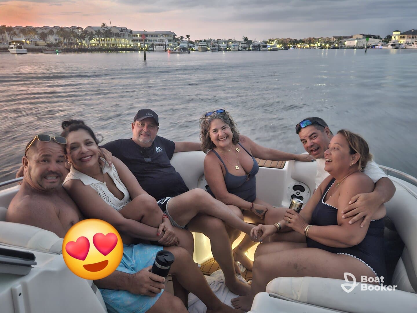 A joyful group of friends enjoys a fun evening on a boat, celebrating together as the sun sets in the background — perfect for memorable outings on the water.