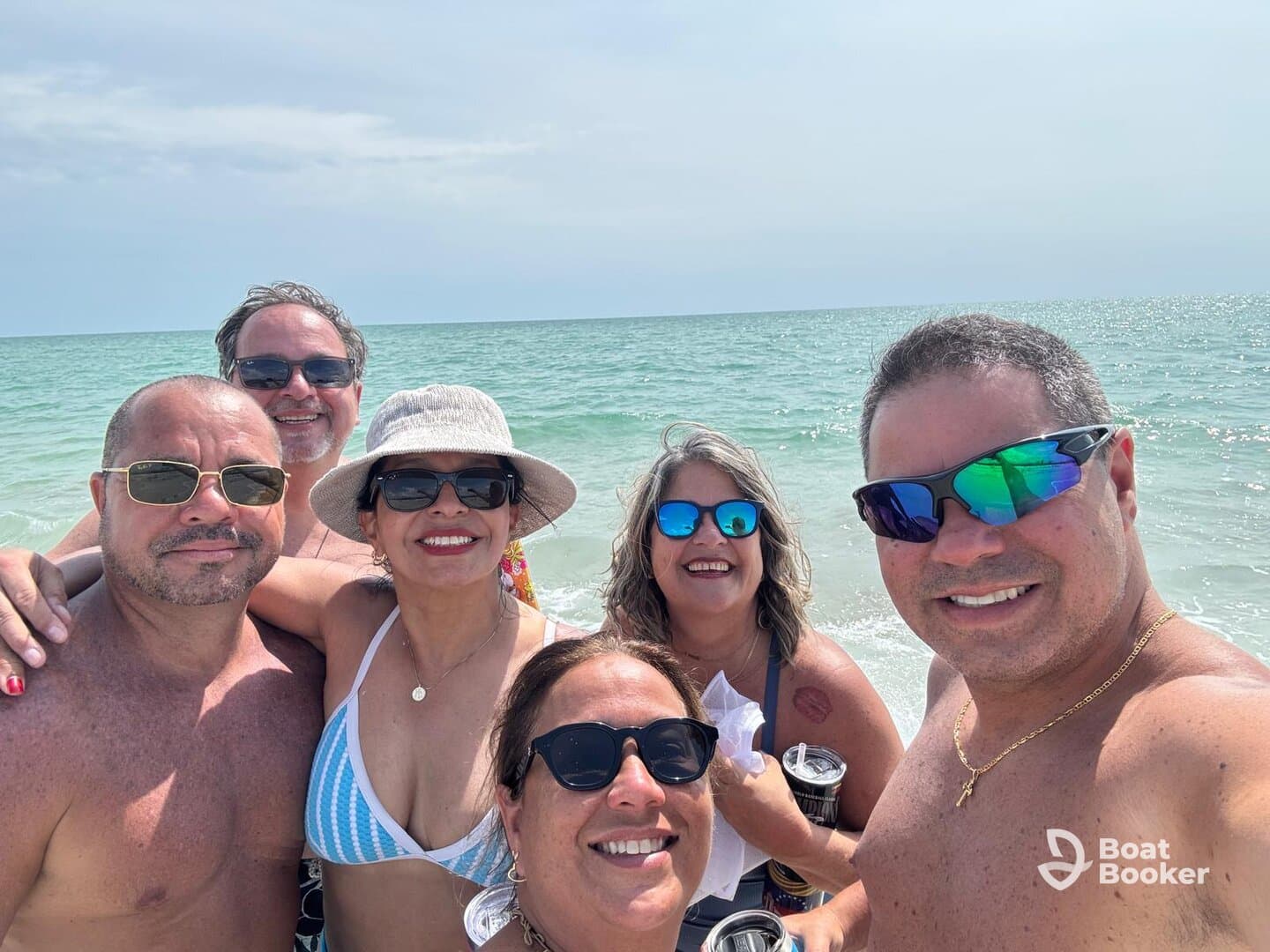 A cheerful group of friends enjoys a sunny day at the beach, capturing memories with smiles and drinks in hand — perfect for summer celebrations and beach outings.