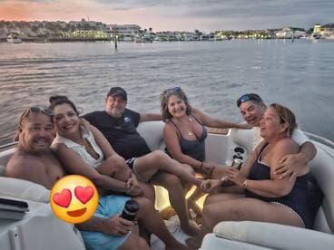 A joyful group of friends enjoys a fun evening on a boat, celebrating together as the sun sets in the background — perfect for memorable outings on the water.