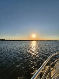 A serene sunset view from the deck of a boat, reflecting golden hues on the water's surface — perfect for capturing the tranquility of evening cruises.