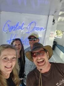 A cheerful group poses for a selfie aboard the 'Crystal Dawn' boat, capturing the joy of their boating experience.