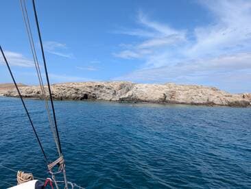 A stunning view of a rocky coastline from a boat, showcasing the beautiful blue waters and clear skies — perfect for island-hopping adventures.